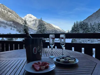 a wooden table with two glasses of wine and food at French Alps Luxury in Vallorcine