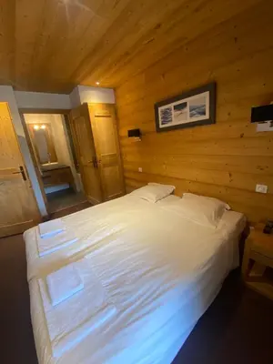a large white bed in a room with wooden walls at French Alps Luxury in Vallorcine