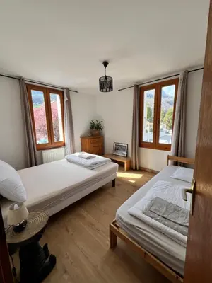 two beds in a room with two windows at Duplex Sallanches - Terrasse, Centre & Parking by AlpenlySallanches in Sallanches