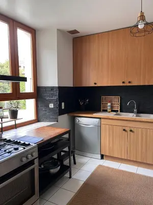 a kitchen with wooden cabinets and a sink and a stove at Duplex Sallanches - Terrasse, Centre & Parking by AlpenlySallanches in Sallanches