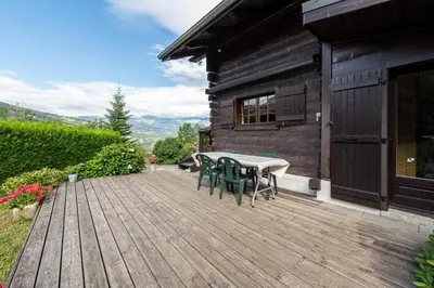 a wooden deck with a table and chairs on a house at Chalet du Brey - Avec terrasse et jardin in Saint-Gervais-les-Bains