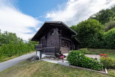 a small wooden house with a bench next to a road at Chalet du Brey - Avec terrasse et jardin in Saint-Gervais-les-Bains
