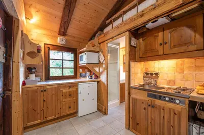 a kitchen with wooden cabinets and a white refrigerator at Chalet du Brey - Avec terrasse et jardin in Saint-Gervais-les-Bains