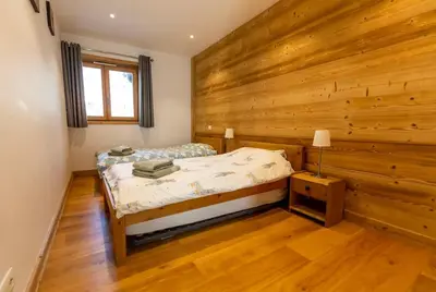 a bedroom with a bed and a wooden wall at Grand Paradis B01 - Modern with great location in Chamonix-Mont-Blanc