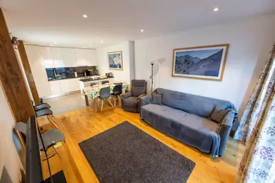 a living room with a blue couch and a kitchen at Grand Paradis B01 - Modern with great location in Chamonix-Mont-Blanc