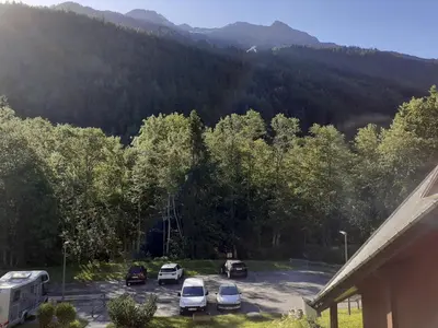 a parking lot with cars parked in front of a mountain at Appartement vue montagne proximité ski et parcours TMB in Les Contamines-Montjoie
