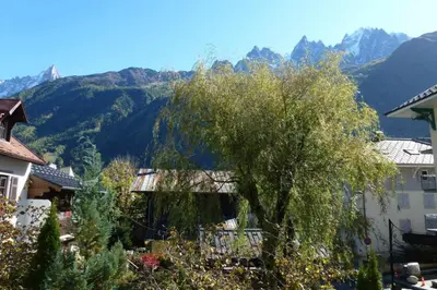 a tree in a town with mountains in the background at Cosy cocoon in the heart of Chamonix in Chamonix-Mont-Blanc