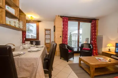 a living room with a red couch and chairs and a table at Cosy cocoon in the heart of Chamonix in Chamonix-Mont-Blanc