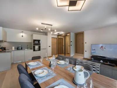 a dining room and living room with a table and chairs at Bel appartement à Megève dans résidence avec piscine - FR-1-569-105 in Megève