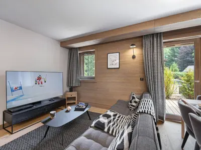 a living room with a couch and a large screen tv at Bel appartement à Megève dans résidence avec piscine - FR-1-569-105 in Megève