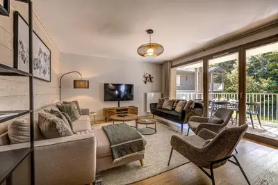a living room with a couch and chairs and a tv at White Pearl Apartments in Chamonix-Mont-Blanc