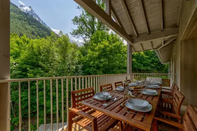 a porch with a wooden table and chairs on a balcony at White Pearl Apartments in Chamonix-Mont-Blanc