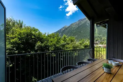 a balcony with a wooden table and chairs and mountains at White Pearl Apartments in Chamonix-Mont-Blanc