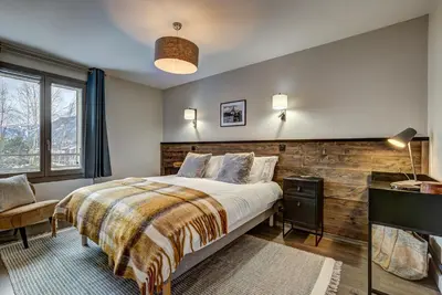 a bedroom with a bed and a wooden wall at White Pearl Apartments in Chamonix-Mont-Blanc