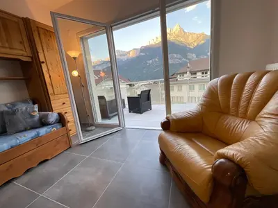 a living room with a couch and a view of a mountain at Appartement au pied du Mont-Blanc 2! in Sallanches