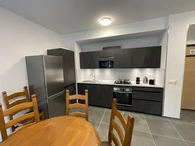 a kitchen with a table and chairs and a kitchen with a refrigerator at Appartement au pied du Mont-Blanc 2! in Sallanches