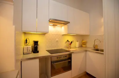 a kitchen with white cabinets and a sink at Majestic T2 calme, spacieux, central, avec parking in Chamonix-Mont-Blanc