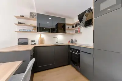 a kitchen with black appliances and a wooden table at Mont-Blanc View - Panoramic Balcony - Chamonix Centre in Chamonix-Mont-Blanc