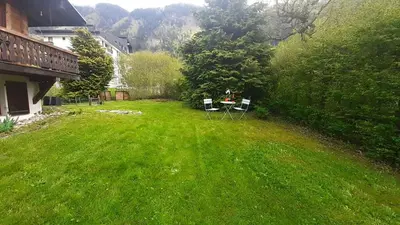 a yard with two chairs and a table in the grass at TellaHouse in Chamonix-Mont-Blanc