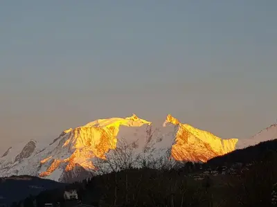 a snow covered mountain with the sun shining on it at Appartement belle vue in Combloux