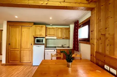 a kitchen with wooden cabinets and a white refrigerator at Second de Cordée in Combloux