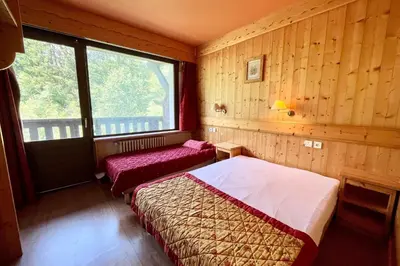 two beds in a room with wooden walls and a window at Second de Cordée in Combloux