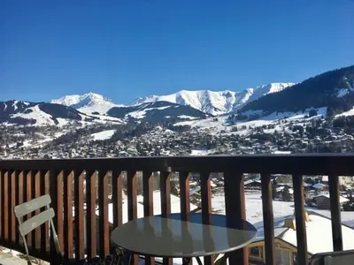 a table and chair on a balcony with snow covered mountains at Appartement 3 pièces à Megève, balcon sud-est, TV et garage ski - FR-1-453-308 in Megève