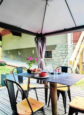 a table and chairs with an umbrella on a deck at les loges de l'Arpenaz in Magland