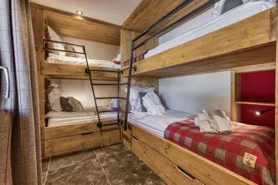 two bunk beds in a room with wooden walls at Chalet Castor in Les Houches