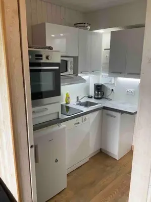 a kitchen with white cabinets and a stove top oven at Studio très lumineux 4 pers in Les Carroz d'Araches