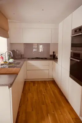a kitchen with white cabinets and a wooden floor at Chalet Oryx in Chamonix-Mont-Blanc