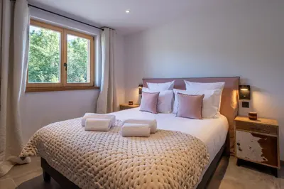 a bedroom with a large bed with pillows and a window at Chalet Ango I Jacuzzi & Hammam I Proche télécabine in Combloux