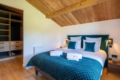a bedroom with a large bed with blue pillows at Chalet Ango I Jacuzzi & Hammam I Proche télécabine in Combloux