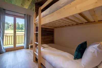a bedroom with two bunk beds and a balcony at Chalet Ango I Jacuzzi & Hammam I Proche télécabine in Combloux