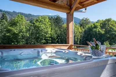 a hot tub on a deck with a view of trees at Chalet Ango I Jacuzzi & Hammam I Proche télécabine in Combloux