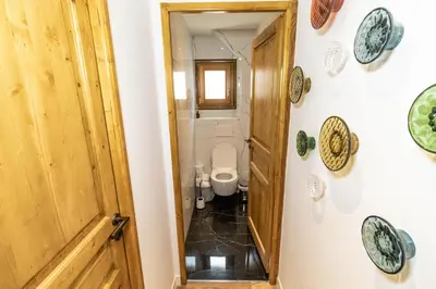 a bathroom with a toilet and a wooden door at Megeve centre ville in Megève