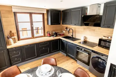 a kitchen with black cabinets and a table with chairs at Megeve centre ville in Megève