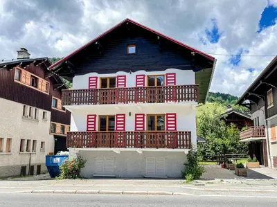a house with red and white shutters and a balcony at Megeve centre ville in Megève