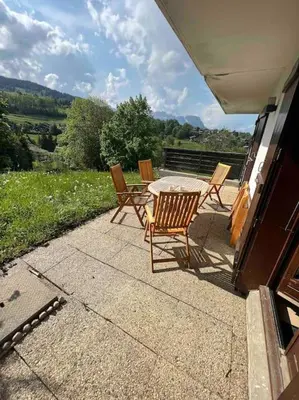 a wooden table and chairs with two cups on it at Appartement chaleureux Megève in Demi-Quartier