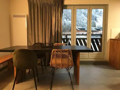 a dining room with a table and chairs and a balcony at Lyret - Centre ville, vue MontBlanc, parking, wifi in Chamonix-Mont-Blanc