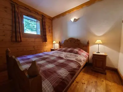 a bedroom with a bed in a log cabin at Appartement 3 pièces cosy, 6 personnes, près de la piscine et du ski bus, parking inclus. - FR-1-572-285 in Arâches-la-Frasse
