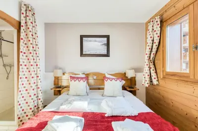 a bedroom with a bed with red and white pillows at Résidence Les Fermes du Soleil - maeva Home - Appartement 3 Pièces 6 Personnes - Sélection MAE-6505 in Les Carroz d'Araches