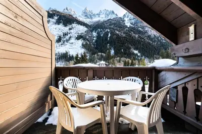 a table and chairs on a balcony with snow covered mountains at Résidence La Ginabelle - maeva Home - Appartement 2 Pièces 4 Personnes - Sélection MAE-9584 in Chamonix-Mont-Blanc