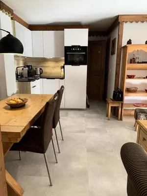a living room with a table and a kitchen at Résidence La Ginabelle - maeva Home - Appartement vue mont blanc 3 pièces 6 personnes avec parking - Prestige MAE-8604 in Chamonix-Mont-Blanc