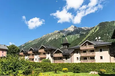 a large apartment building with mountains in the background at Résidence La Ginabelle - maeva Home - Appartement 3 pièces 6 personnes - Prestige MAE-3904 in Chamonix-Mont-Blanc