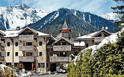 a large building with snow covered mountains in the background at Résidence La Ginabelle - maeva Home - Appartement 3 pièces 6 personnes - Prestige MAE-3904 in Chamonix-Mont-Blanc