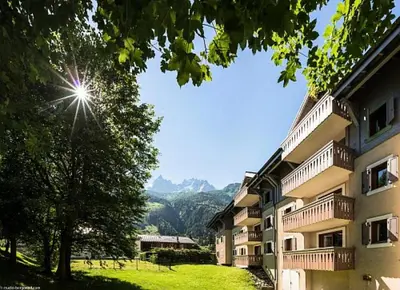a view of a building with mountains in the background at Résidence La Ginabelle - maeva Home - Appartement 3 pièces 6 personnes - Prestige MAE-4054 in Chamonix-Mont-Blanc