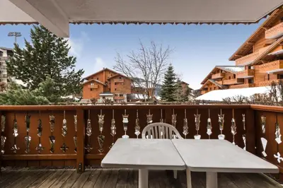 a wooden deck with a white table and chair at Résidence Les Fermes du Soleil - maeva Home - Appartement 3 pièces 6 personnes - Sélection MAE-8007 in Les Carroz d'Araches