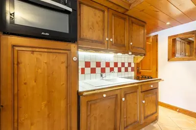 a kitchen with wooden cabinets and a sink and a microwave at Résidence Les Fermes du Soleil - maeva Home - Appartement 3 pièces 6 personnes - Sélection MAE-8007 in Les Carroz d'Araches
