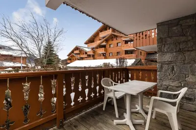 a wooden balcony with a table and two chairs at Résidence Les Fermes du Soleil - maeva Home - Appartement 3 pièces 6 personnes - Sélection MAE-8007 in Les Carroz d'Araches